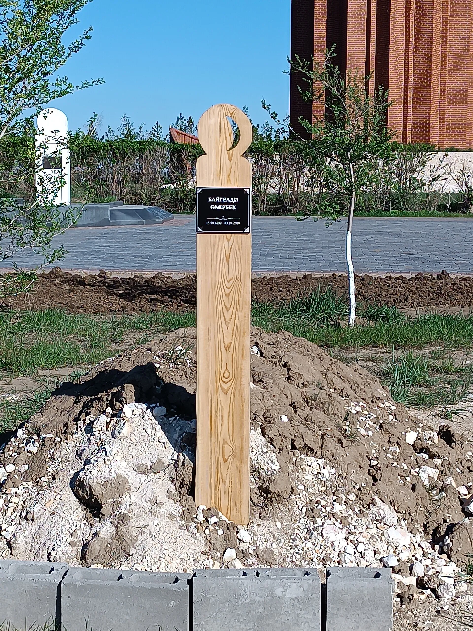 Ұлттық пантеондағы Өмірбек Байкелдінің жатқан орнына қойылған құлпыағаш (құлпыбелгі).