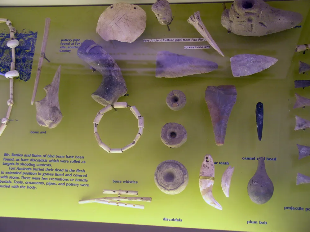 A selection of tools and other artifacts from the Fort Ancient culture on display in a museum in Maysville, Ky. Includes bone awls, stone discoidals used for the gane of chunkey, beads and pendants and ceramic pipes. Some of the artifacts are from the Fox Fields site.