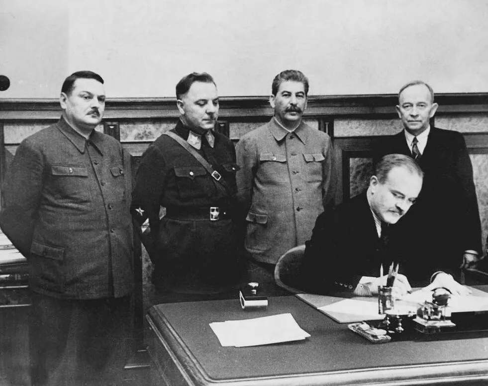 Picture of V. Molotov signing state treaty between (soviet installed) Finnish People's Government and Soviet Union. Finnish head of People's Government Otto Ville Kuusinen (far right, standing), whom Stalin appointed to head a “People’s Government” for Finland, December 1, 1939. Zhdanov and Voroshilov are to Stalin’s right.
